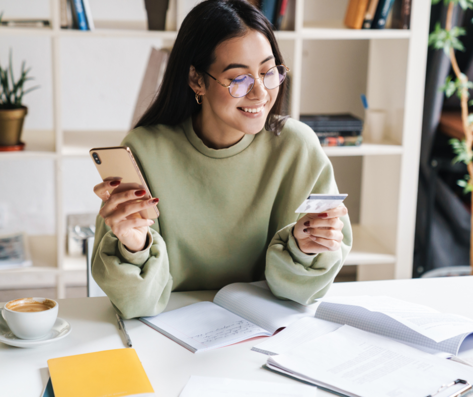 Student holding a phone and a card for transaction